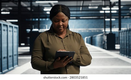 Server facility software engineer checks server facility metrics on a digital tablet to enhance operational effectiveness. Woman in data center working with app device analytics to predict performanc.