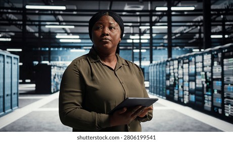 Server facility software engineer checks server facility metrics on a digital tablet to enhance operational effectiveness. Woman in data center working with app device analytics to predict performanc.