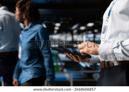 Server farm data scientist using tablet to review AI LLM visualization, intelligent systems for operational stability. Engineer analyzes neural network outputs for stable operations.