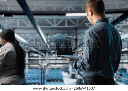 Server farm engineer using laptop to visualize AI model outputs on screen. IT professional using notebook to upgrade enterprise data center rigs generating AI visualizations