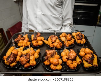 Server presenting assorted Nigerian small chops platter, featuring puff-puff, grilled chicken, samosas, and spring rolls at a social event in Lagos