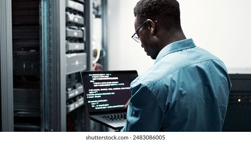 Server room, black man or coding with laptop for system upgrade, cybersecurity or screen. Software management, data or male programmer with digital for problem solving, analytics or troubleshooting