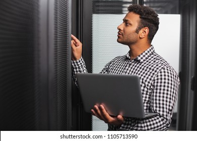 Server Room. Focused IT Guy Using Laptop And Pointing At Hardware