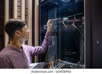 In The Server Room A Technician/ It Engineer/ Connecting The Internet Network Cable And Adjusting On The Notebook