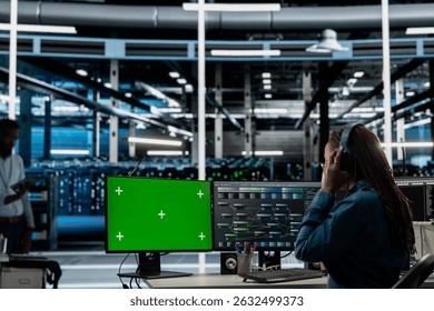 Servers room employee wearing audio headset doing maintenance using mockup PC. Technician in data center using green screen computer to check equipment performance, listening music