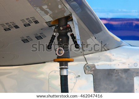 Service airplane before departure. The process of refueling. Fuel hose inserted in the aircraft wing.
