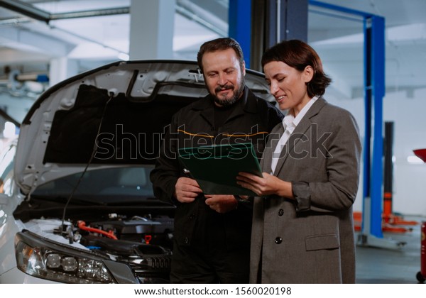 Service auto center mechanic\
have a conversation with the customer woman they shows signed\
documents