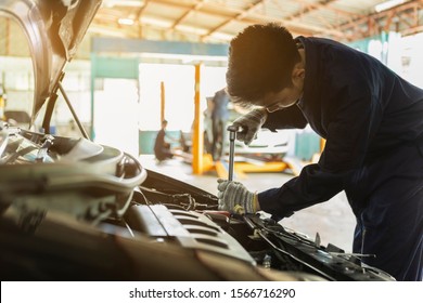 Service Car Bonnet Mechanic. Asian Man Auto Mechanic Using A Wrench And Screwdriver To Working Service Car In The Garage.