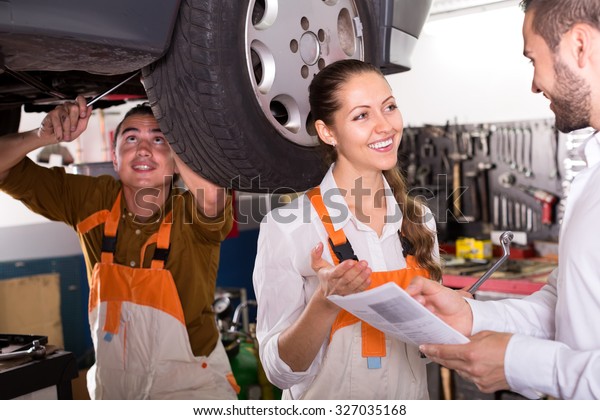Service\
crew and driver standing near car and\
smiling