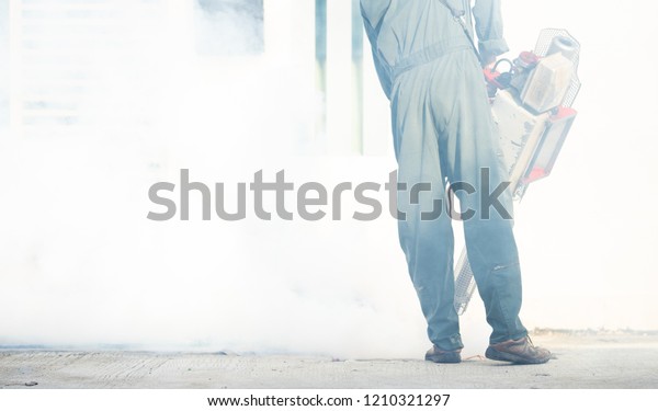Service Employee pest control man in uniform\
trying killing insects and fogging to eliminate mosquito for\
preventing spread dengue fever and zika virus.Worker fogging\
residential area with\
chemical.
