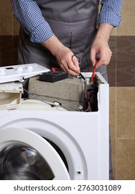 A service engineer tests the integrity of the circuits and the functionality of capacitor. Professional repair of household appliances.