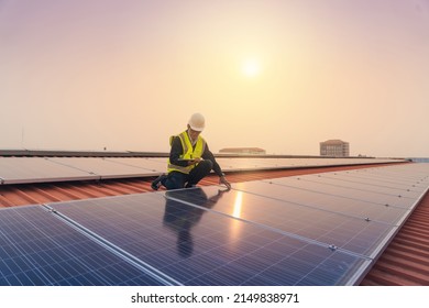 El ingeniero de servicios utiliza una celda solar de instalación de inspección de trabajo de tableta en el techo. Técnico mantenimiento de celdas solares en la fábrica de techos bajo la luz solar de la mañana. Tecnología de energía solar renovable.