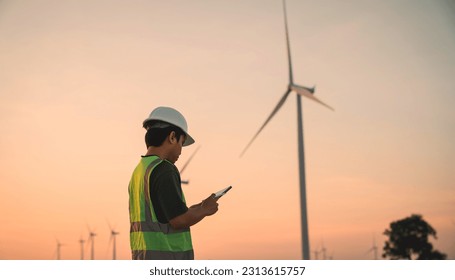 Service engineers checking system of windmill with tablet. Wind turbines generate electricity. Clean and Renewable energy concept.