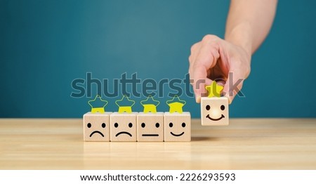 Service exceeds business expectations, the best customer experience rating. satisfaction survey concept Businessman's hand selecting a smiley face on a wooden cube 5 star satisfaction