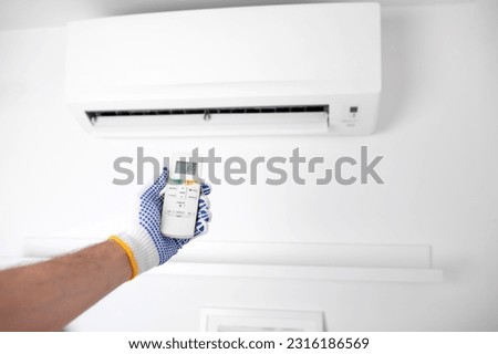 Service guy holding a remote controller of a modern air condition unit.