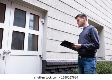 Service Man Holding Clipboard In Hand Standing In Front Of Closed Door - Shutterstock ID 1389187964