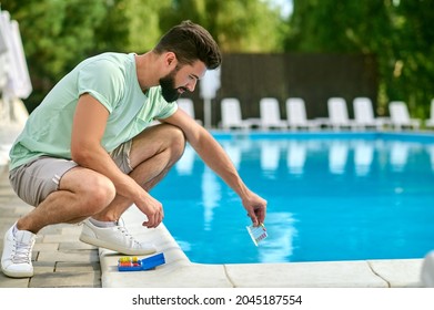 A Service Man Making A Water Test In A Swimming Pool