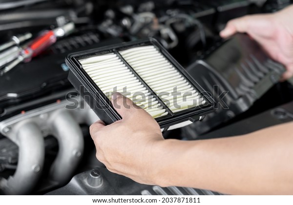 Service man\
replace the old engine air filter compared to the new one in engine\
room : Home service car\
concept