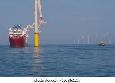 Service operational vessel in dynamic position mode alongside wind turbine with small crew transfer vessel operating in the field - Powered by Shutterstock