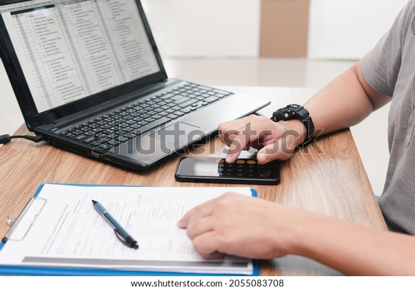Service staff use smartphone calculate cost of
repairing the car from the damage assessment document and use
laptop on table office service
center
