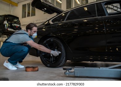 Service Station Worker Coating The Car Tire With Black Gloss