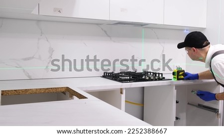 A service technician installs a gas stove in the kitchen using an electronic laser. 