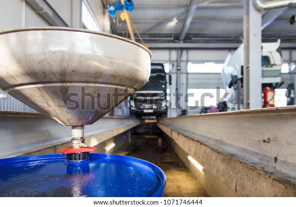 Service of trucks. Oil change\
in service center. waste oil drain system on a blurred truck\
background