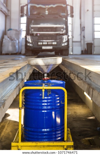 Service of trucks. Oil change\
in service center. waste oil drain system on a blurred truck\
background