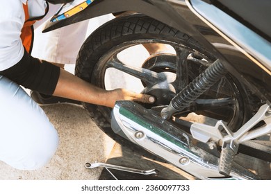 Service worker changing motorcycle tire installation in the workshop for motorcycle repairment with soft-focus and overlight in the background - Powered by Shutterstock