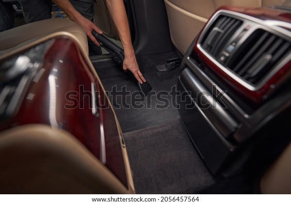 Service worker\
cleaning car with vacuum\
cleaner