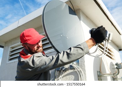 Trabajador de servicio instalando e instalando antena satelital para la televisión por cable