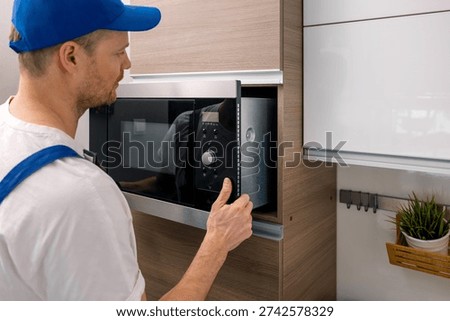 service worker installing integrated microwave oven in the domestic kitchen. household appliance maintenance and repair