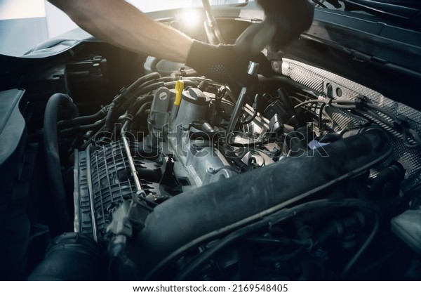 Serviceman changes spark plugs in modern turbocharged\
engine. Timely maintenance and replacement of consumables in\
car