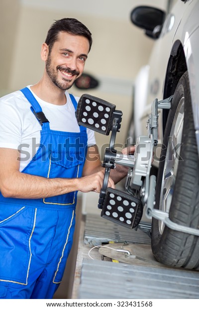 serviceman\
checking wheel alignment in a car workshop  \
