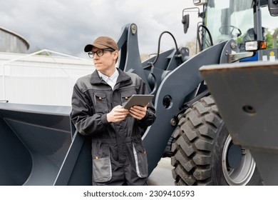 Serviceman with digital tablet on a background of the tractor