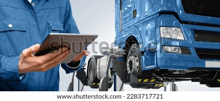 Serviceman with digital tablet on the background of the truck in the car service