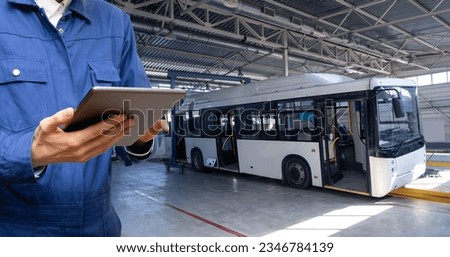 Serviceman with digital tablet on the background of the bus in the garage.