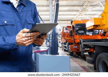 Serviceman with digital tablet on the background of the truck in the garage