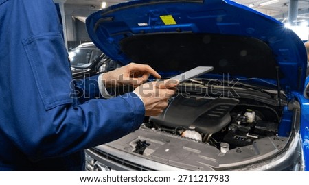 Serviceman with digital tablet on the background of the car in the car service	