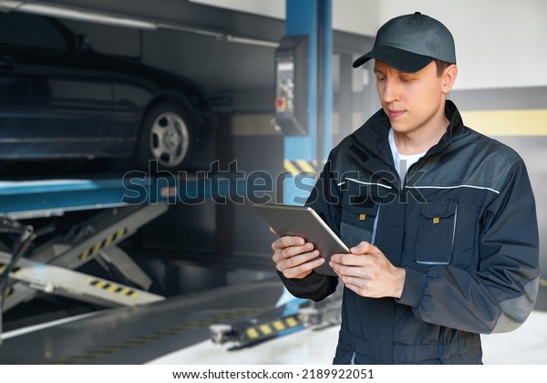 Serviceman with digital tablet on a background of\
column lift at car\
service