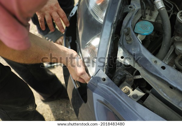 a serviceman hands fixing a car bumper, outdoor\
shot                         \
