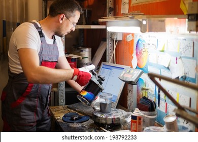 Serviceman Mixing Paint In A Car Body Workshop