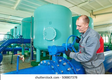 serviceman operating industrial water purification or filtration equipment