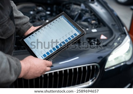 Serviceman with tablet checks car software in car service.