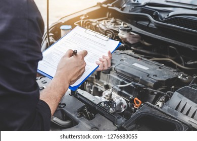 Services car engine machine concept, Automobile mechanic repairman checking a car engine with inspecting writing to the clipboard the checklist for repair machine, car service and maintenance. - Shutterstock ID 1276683055