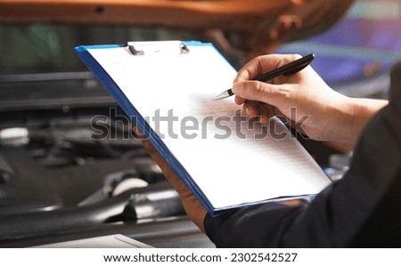 Services car engine machine concept, Automobile mechanic repairman checking a car engine with inspecting writing to the clipboard the checklist for repair machine, car service and maintenance.