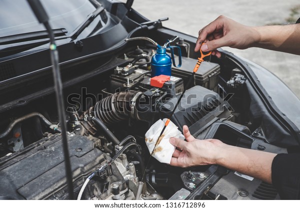 Services car\
engine machine concept, Automobile mechanic repairman hands\
checking a car engine automotive with oil level in the engine\
transportation, car service and\
maintenance.