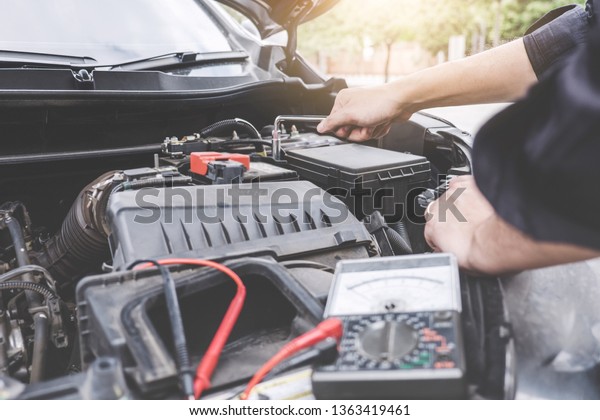 Services car engine machine concept,\
Automobile mechanic repairman hands repairing a car engine\
automotive workshop with a wrench and digital multimeter testing\
battery, car service and\
maintenance.