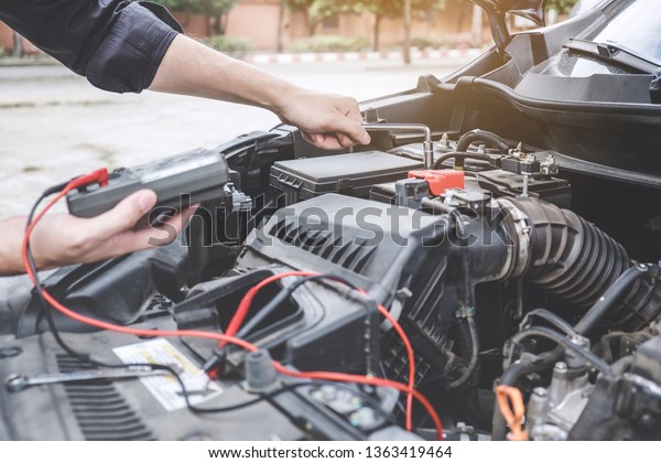 Services car engine machine concept,\
Automobile mechanic repairman hands repairing a car engine\
automotive workshop with a wrench and digital multimeter testing\
battery, car service and\
maintenance.