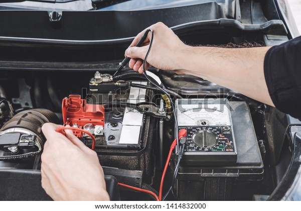 Services\
car engine machine concept, Automobile mechanic repairman hands\
checking a car engine automotive workshop with digital multimeter\
testing battery, car service and\
maintenance.